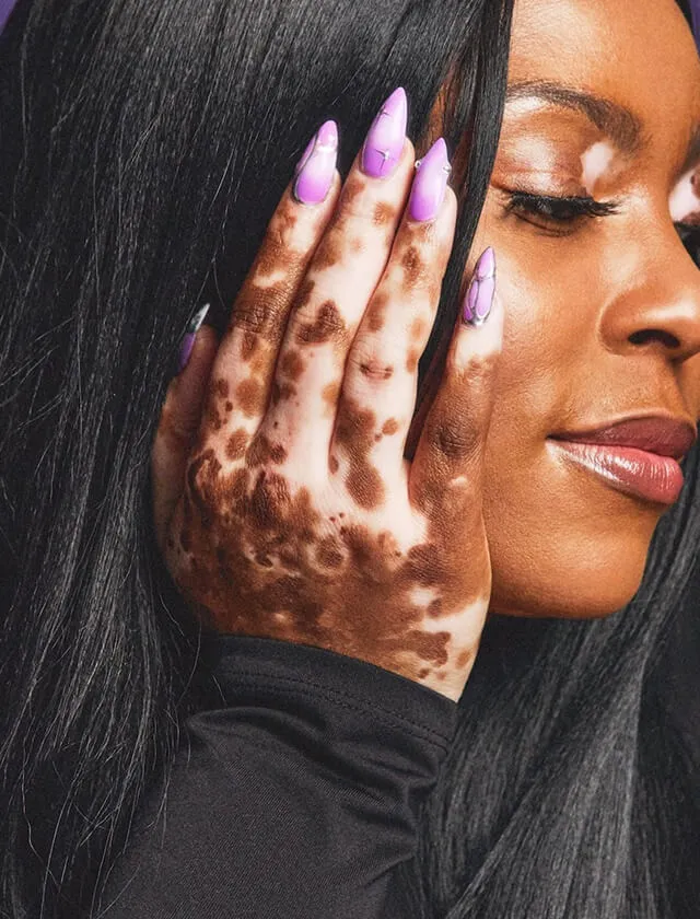 A nail tech with a pink manicure holding her hand on her face.